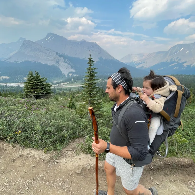 The trail begins through subalpine meadows with mountain views stretching in every direction