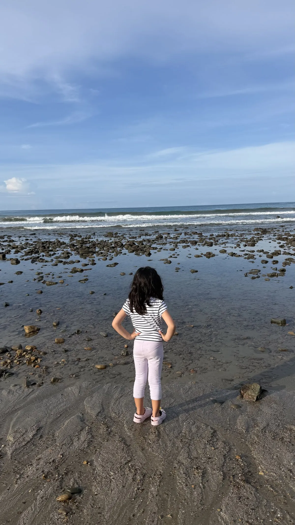 A child exploring the rocky shoreline at Playa El Remanso